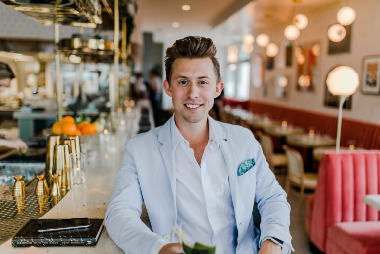 A young man sitting on a bar, smiling and looking wealthy