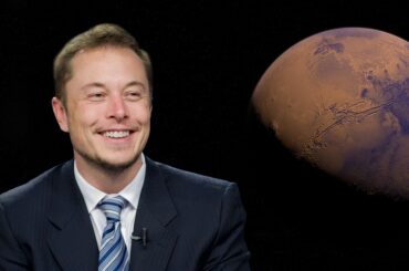 Elon Musk in blue suit smiling while image of mars shows behind